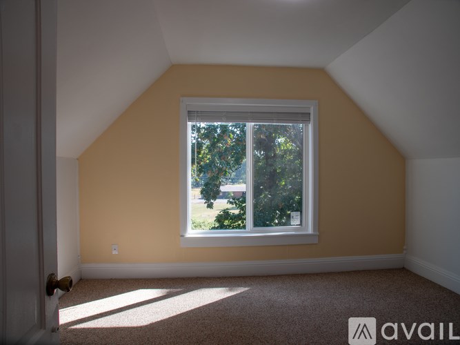 A room with a window and a carpeted floor.