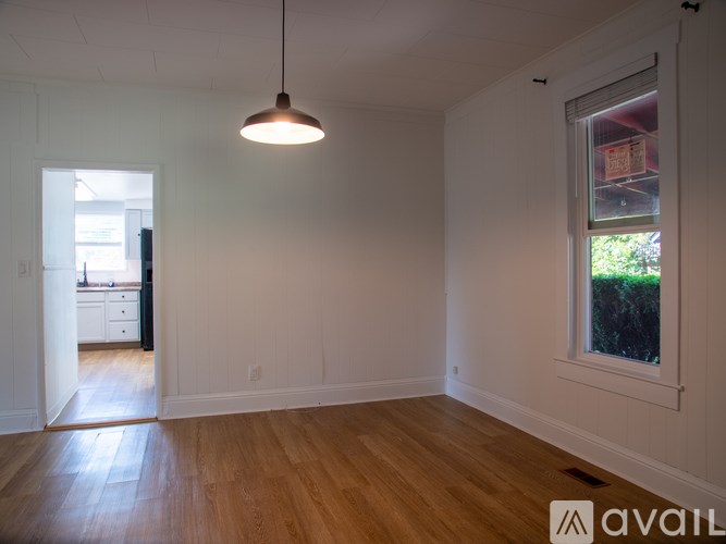 A room with wooden floors and a window showing greenery outside.