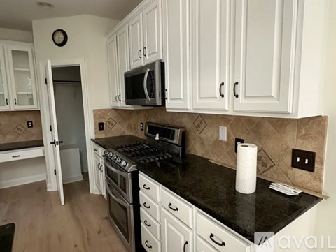 A kitchen with white cabinets and a black countertop.