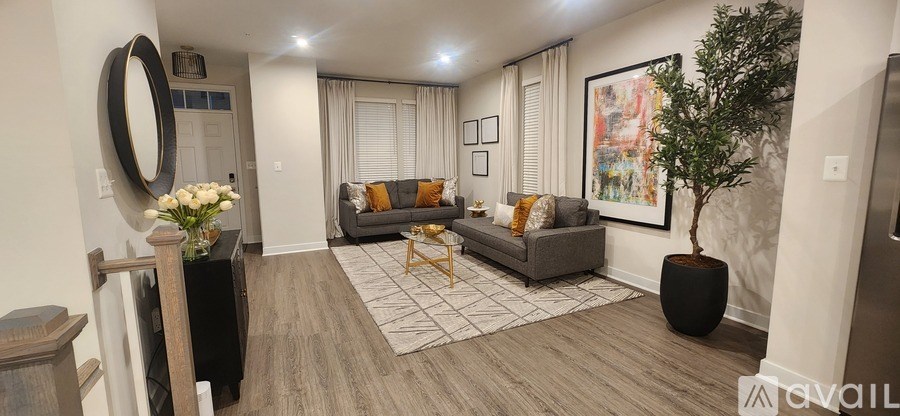 A living room with a grey couch, a coffee table, a rug, a plant, and a framed picture on the wall.