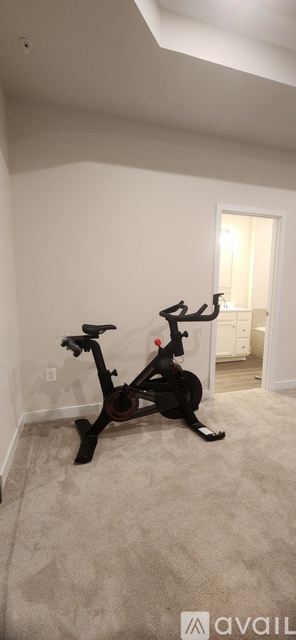 A black exercise bike is in a room with white walls.