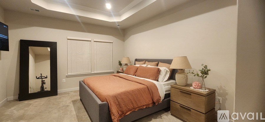 A bedroom with a bed, nightstand, and a mirror.