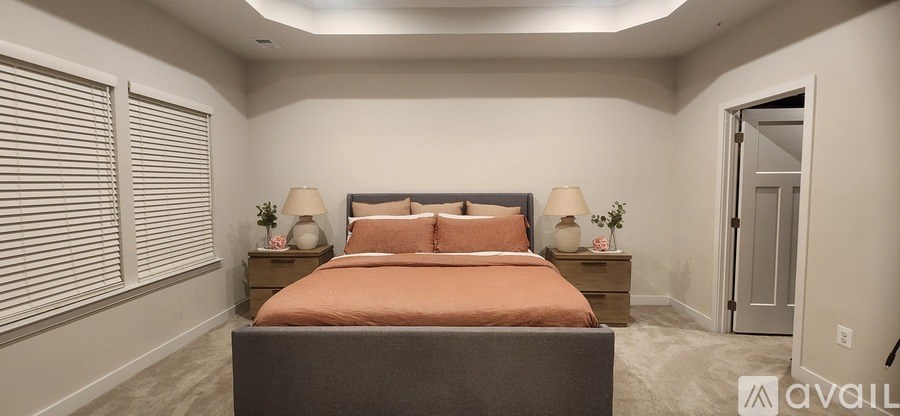 A bedroom with a bed, two nightstands, and a door.