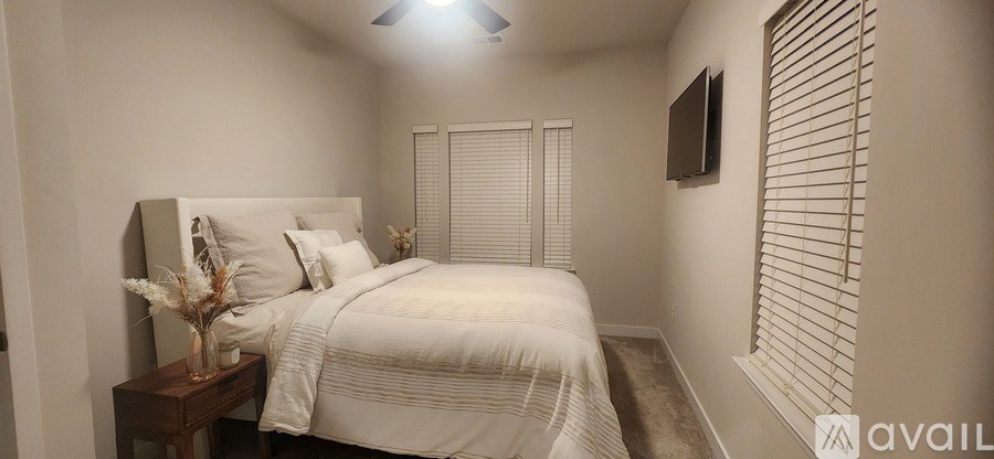 A bedroom with a bed, nightstand, and window with blinds.