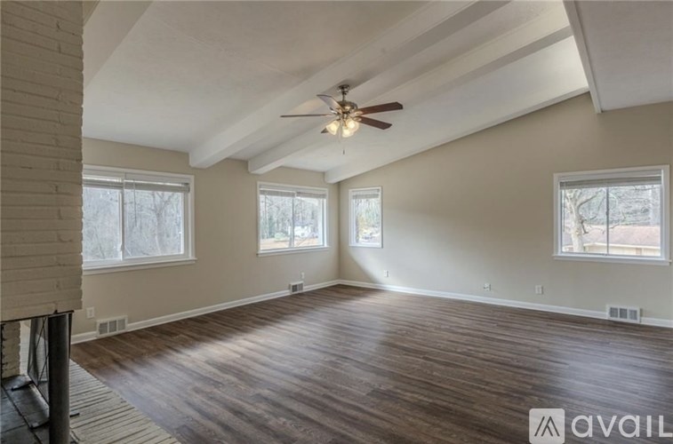A room with a ceiling fan and wooden flooring.
