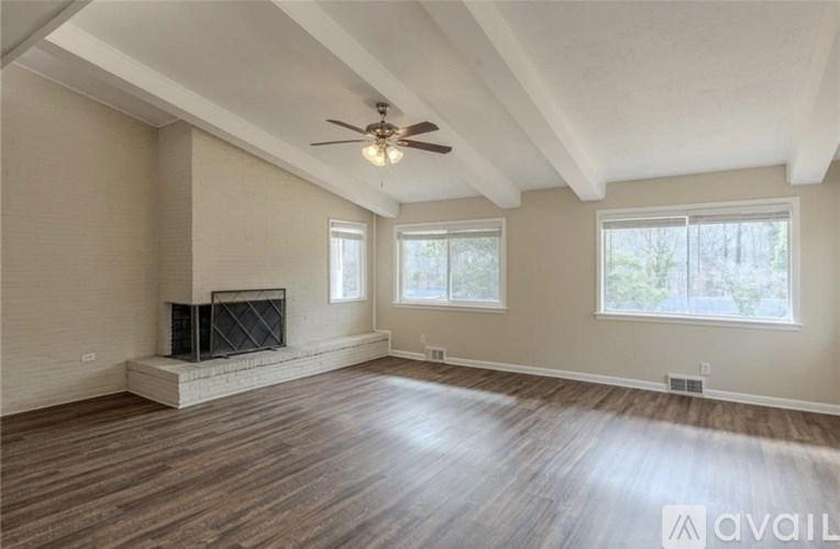 A spacious living room with a fireplace and a ceiling fan.