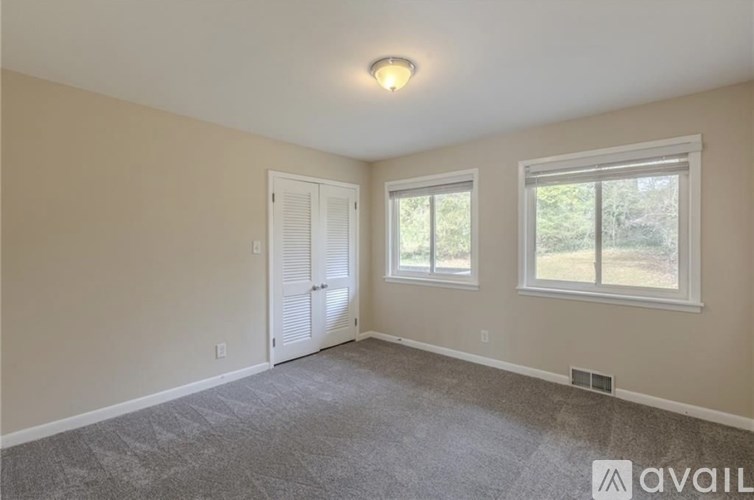 A room with a carpeted floor, a window, and a door.