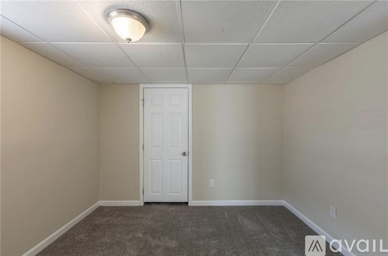 A room with a white door and carpeted floor.