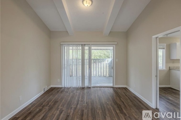 A room with wooden floors and a sliding glass door leading to a balcony.