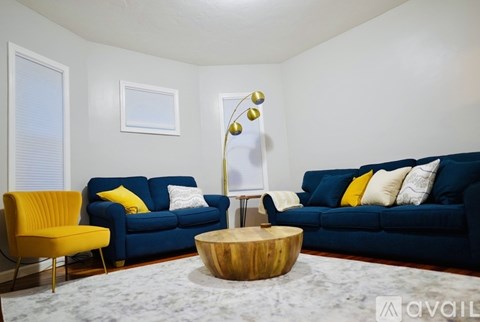 A living room with blue couches and a yellow chair.