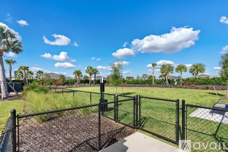 A fenced backyard with a dirt area and a few trees.
