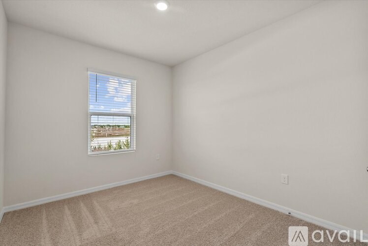 A room with a window showing a view of a building and trees outside.