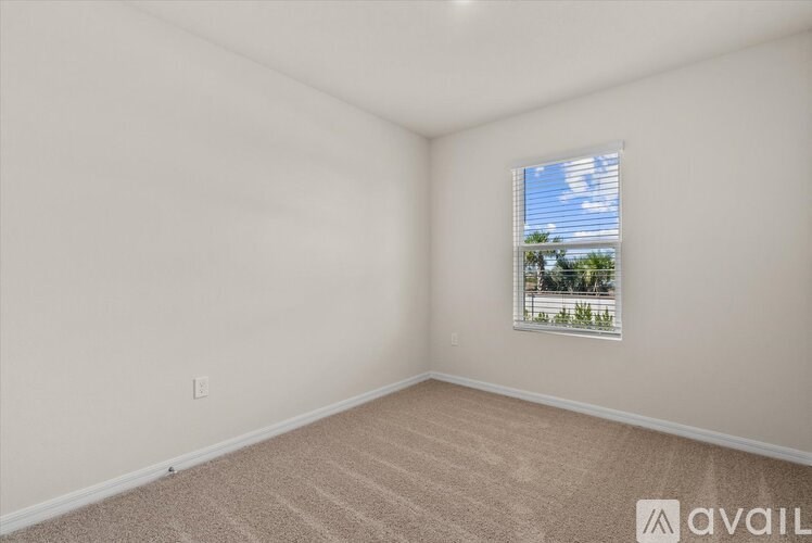 A room with a window showing a blue sky and trees outside.