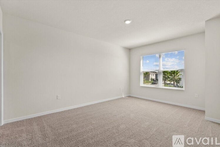 A room with a window showing a view of trees and a car.