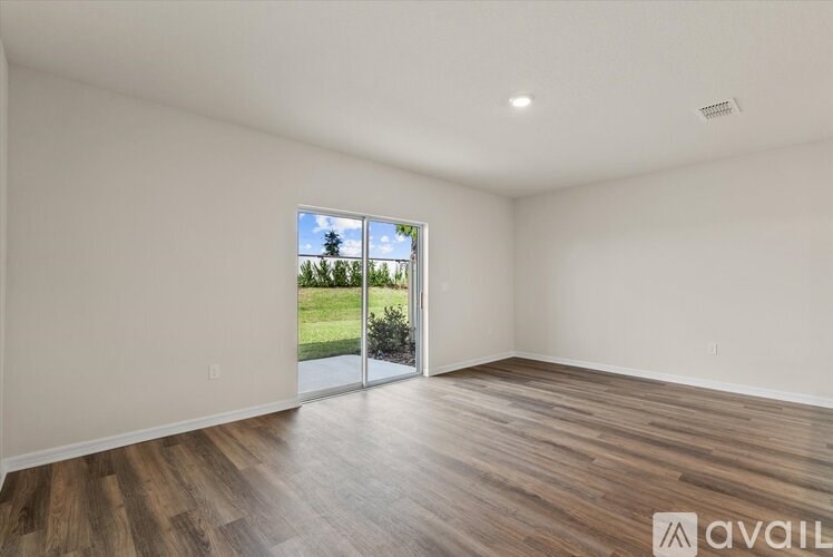 A room with wooden flooring and a sliding glass door leading to a green outdoor area.