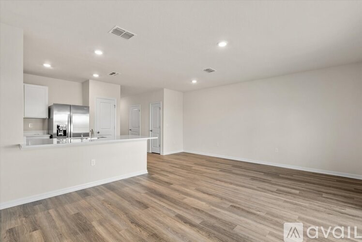 A spacious kitchen with wooden flooring and white walls.