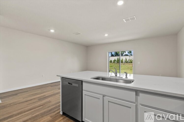 A kitchen with a sink and a window showing a view of trees.