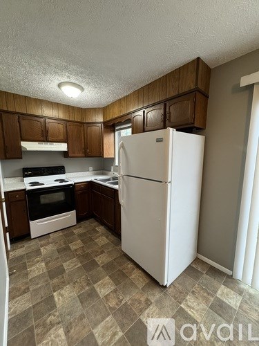 A kitchen with a white refrigerator and brown cabinets.