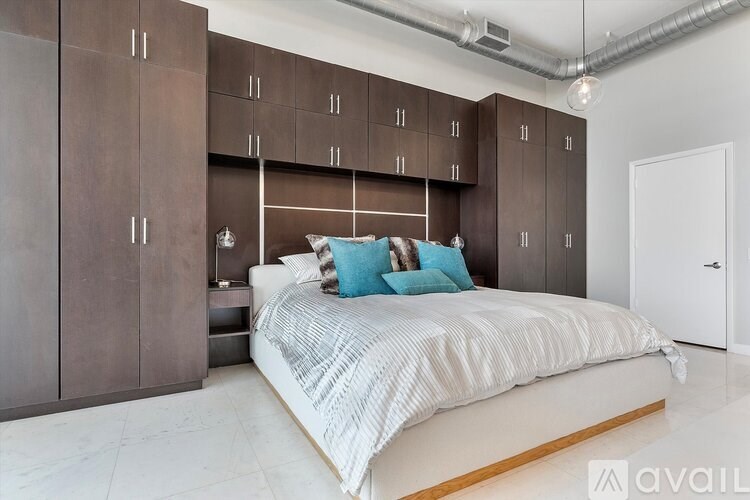 A bedroom with a large bed and brown cabinets.
