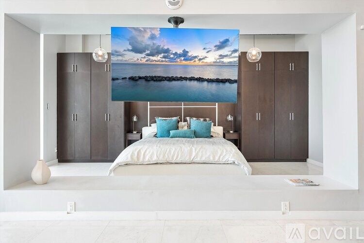 A bedroom with a large bed and a picture of a beach on the wall.