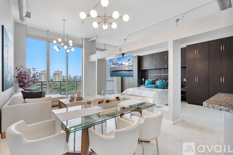 A modern living room with a glass dining table and white chairs.