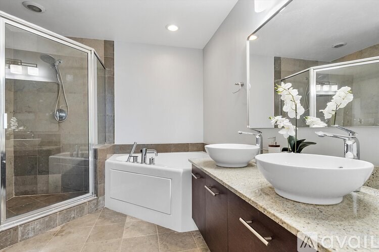 A modern bathroom with a white bathtub and two white sinks.
