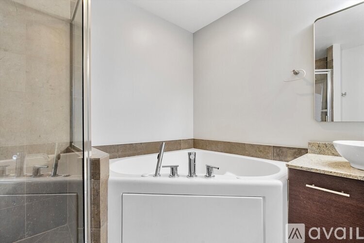 A white bathtub with a silver faucet is in a bathroom with a marble wall.