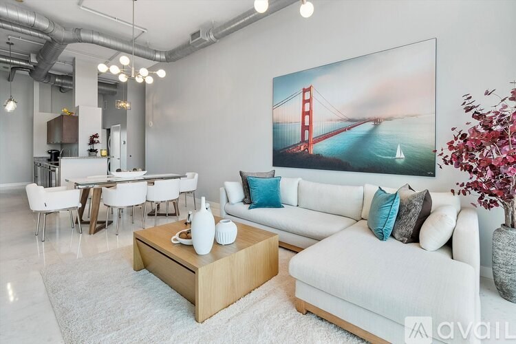 A living room with a white couch, a coffee table, and a large painting of the Golden Gate Bridge.