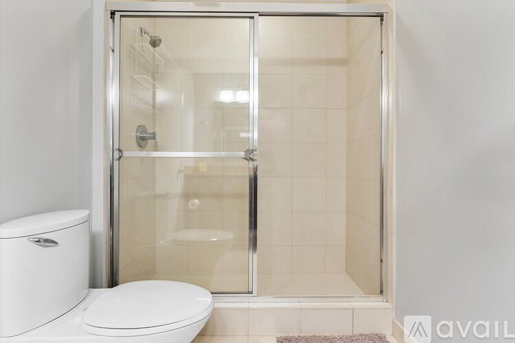 A white toilet sits next to a walk-in shower with a glass door.