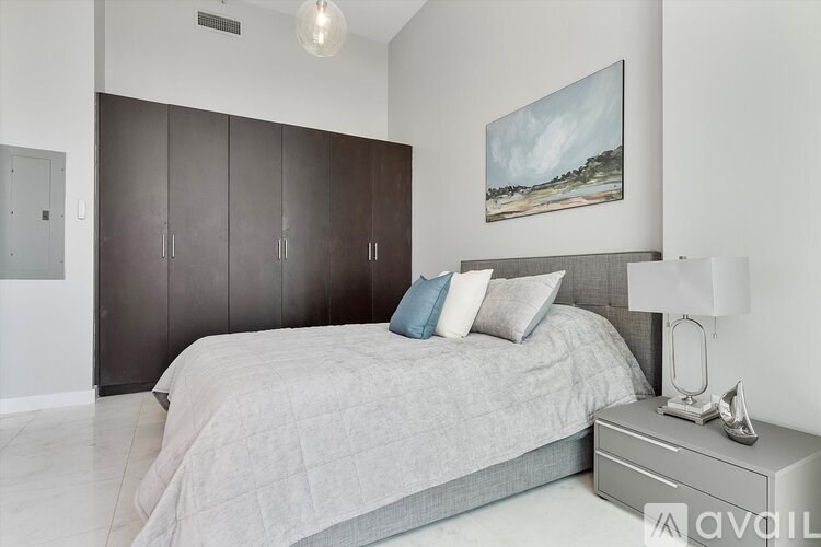 A bedroom with a bed, nightstand, and a painting on the wall.