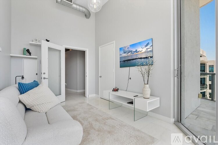 A modern living room with a white sofa and a television on the wall.