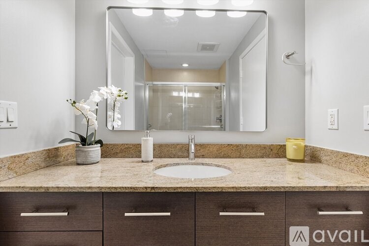 A bathroom with a sink, mirror, and brown cabinets.