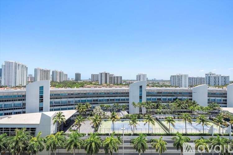 A modern building complex with palm trees in front.