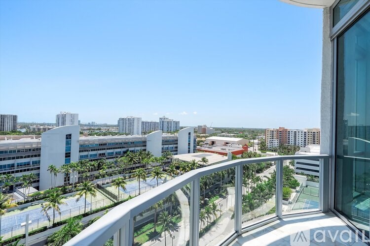 A balcony overlooks a cityscape with palm trees and a clear blue sky.
