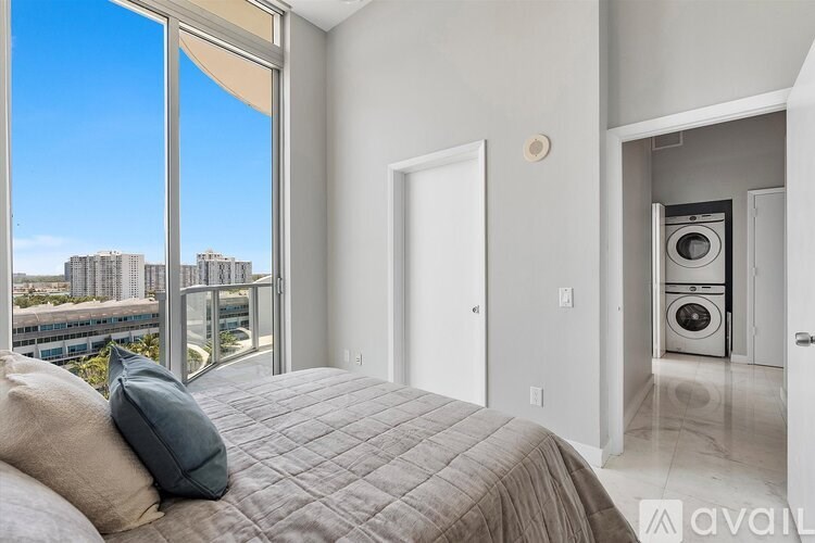 A bedroom with a large bed and a balcony overlooking a cityscape.