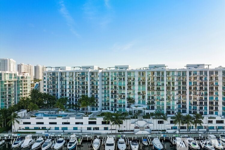 A marina with boats docked in front of a row of buildings.