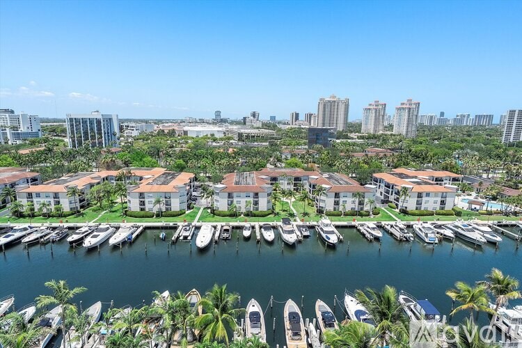 A marina with boats docked in front of a row of houses and buildings in the background.