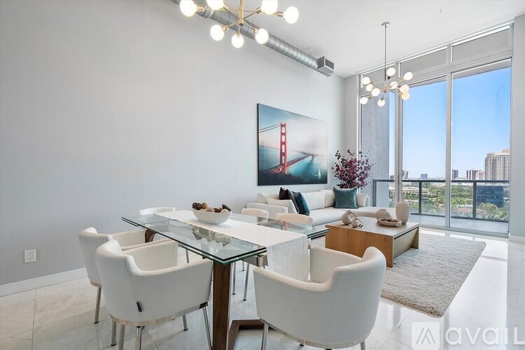 A modern dining room with a glass table and white chairs.