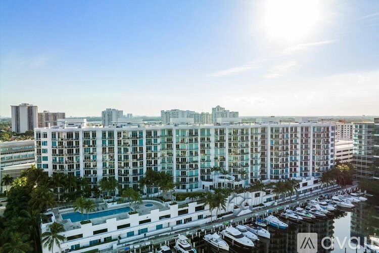 A large white building with a pool in the middle of a marina.
