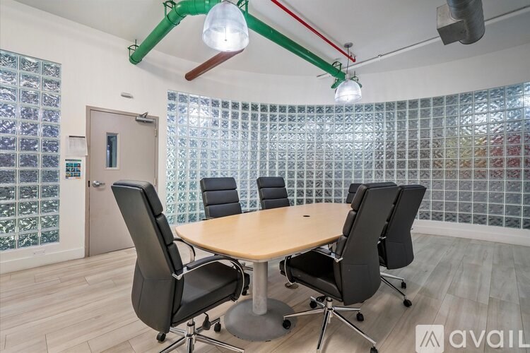 A conference room with a table surrounded by chairs and a glass block wall.