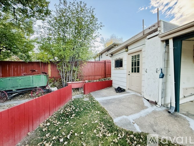 A white house with a red fence and a green wagon in the backyard.