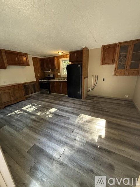 A kitchen with wooden cabinets and a black fridge.