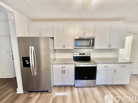 A kitchen with white cabinets and a stainless steel refrigerator.