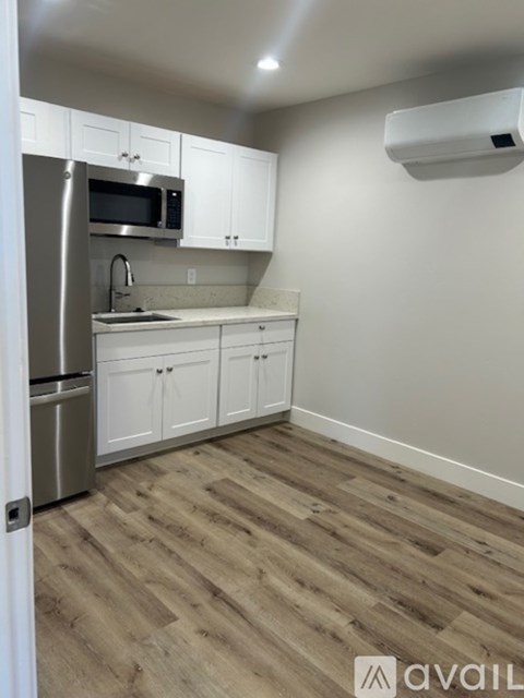 A kitchen with white cabinets and a wooden floor.