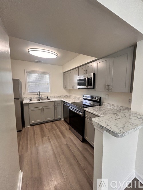 A kitchen with a refrigerator, microwave, oven, and sink.
