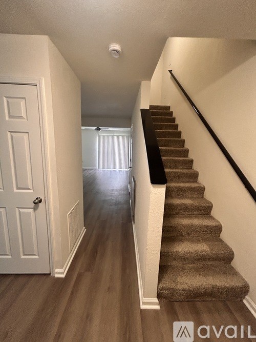 A hallway with a staircase and a white door.