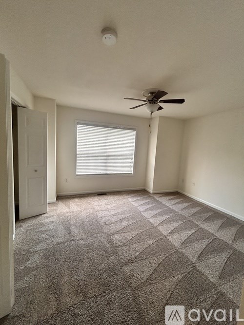 A room with a ceiling fan and a window with blinds.