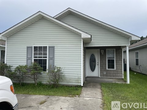 A small house with a grey siding and a white door is available for rent.