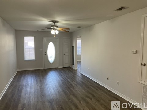 A spacious room with wood flooring and a ceiling fan.