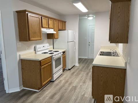 A kitchen with white appliances and wooden cabinets.